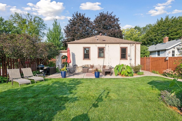 rear view of property featuring outdoor lounge area, an outbuilding, a patio area, and a lawn