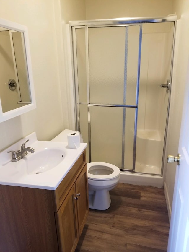 bathroom with toilet, a shower with door, vanity, and hardwood / wood-style flooring