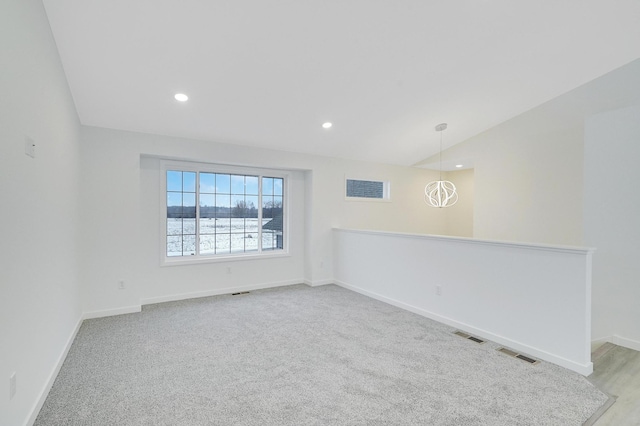 unfurnished room featuring light carpet, a chandelier, and vaulted ceiling