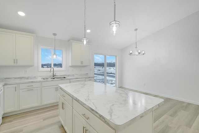 kitchen with sink, decorative light fixtures, white cabinetry, light hardwood / wood-style floors, and a kitchen island