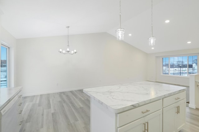 kitchen with vaulted ceiling, light hardwood / wood-style flooring, hanging light fixtures, a kitchen island, and white cabinets