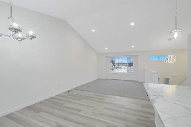 unfurnished living room featuring lofted ceiling, light hardwood / wood-style floors, and a notable chandelier