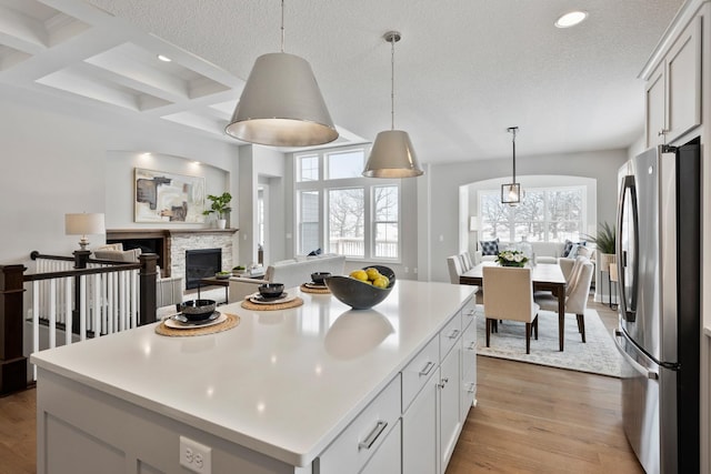 kitchen with coffered ceiling, beam ceiling, white cabinetry, a kitchen island, and stainless steel refrigerator