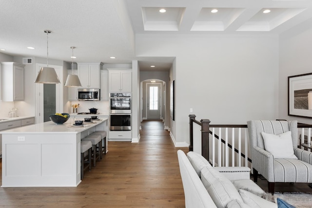 kitchen with pendant lighting, appliances with stainless steel finishes, coffered ceiling, a kitchen island, and beamed ceiling