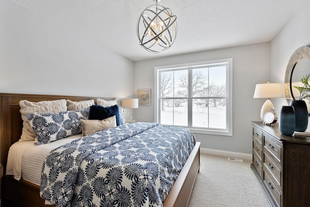 carpeted bedroom with multiple windows, a textured ceiling, and an inviting chandelier