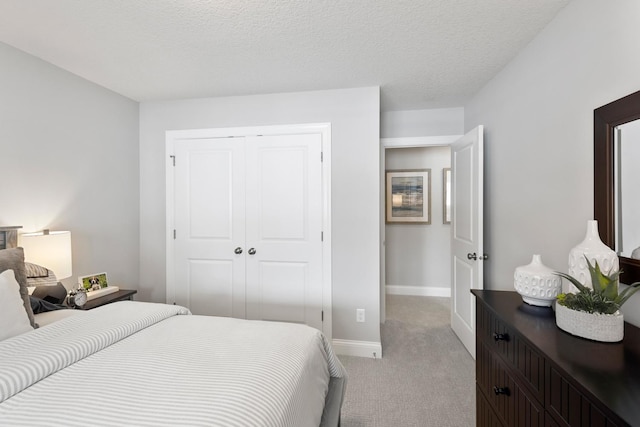 bedroom with a closet, light carpet, and a textured ceiling