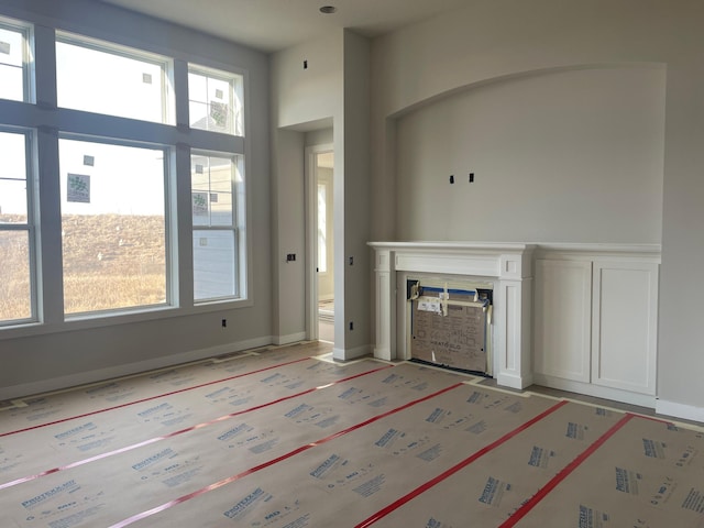 unfurnished living room with a fireplace and a high ceiling