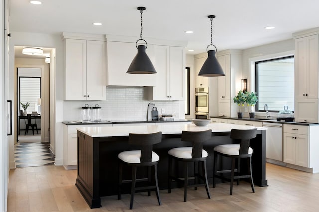 kitchen featuring hanging light fixtures, a kitchen island, stainless steel appliances, and light wood-type flooring