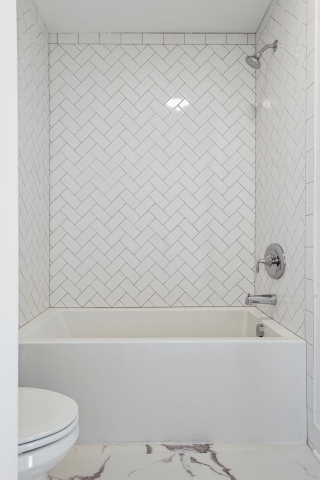 bathroom with tiled shower / bath combo and toilet