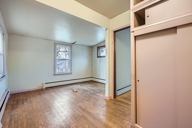 spare room featuring hardwood / wood-style floors, vaulted ceiling, and baseboard heating