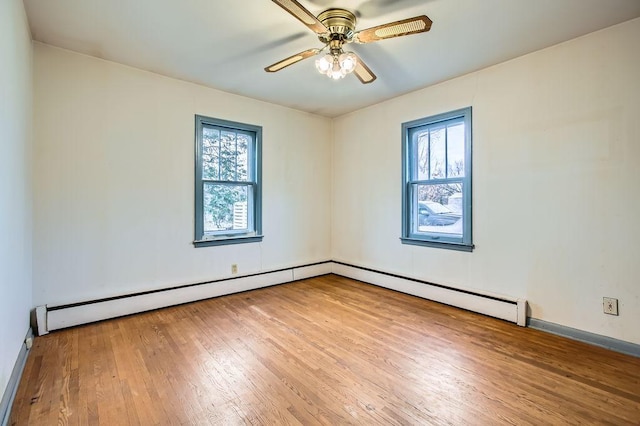 spare room featuring baseboard heating, light hardwood / wood-style flooring, ceiling fan, and a healthy amount of sunlight