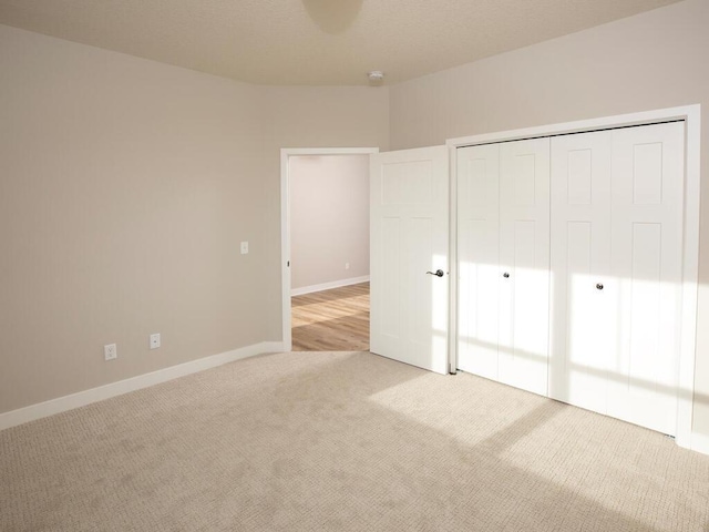 unfurnished bedroom with light colored carpet and a closet