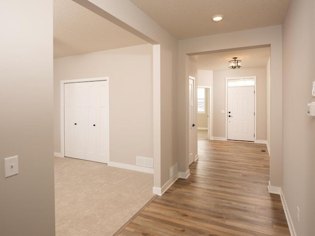 hallway with hardwood / wood-style floors and a textured ceiling