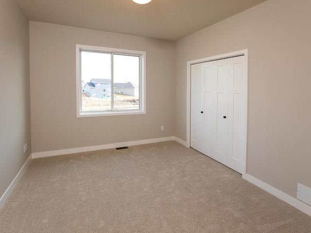 unfurnished bedroom featuring a closet and light colored carpet