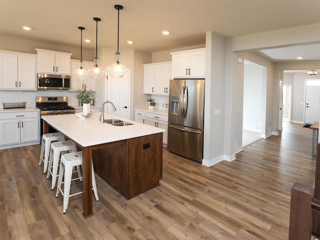 kitchen featuring pendant lighting, sink, dark hardwood / wood-style flooring, white cabinetry, and stainless steel appliances