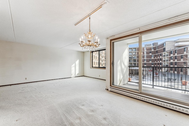 carpeted spare room featuring a textured ceiling and an inviting chandelier