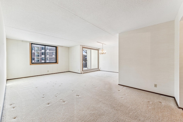 empty room featuring a textured ceiling, carpet floors, and a notable chandelier