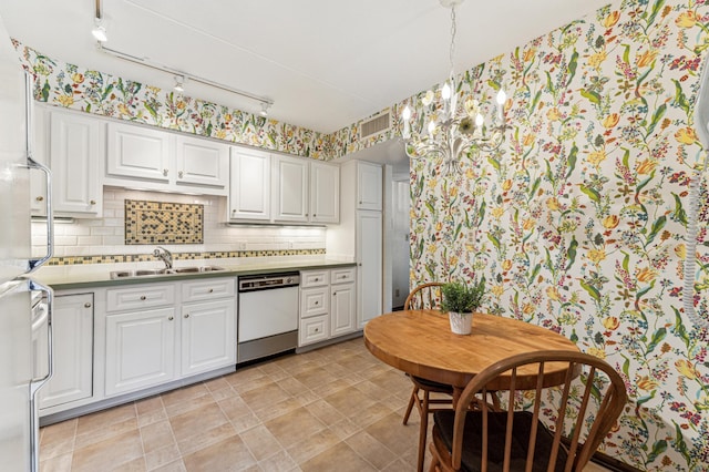 kitchen with dishwasher, sink, backsplash, track lighting, and white cabinets