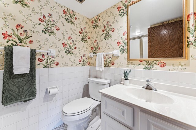 bathroom featuring vanity, tile walls, and toilet