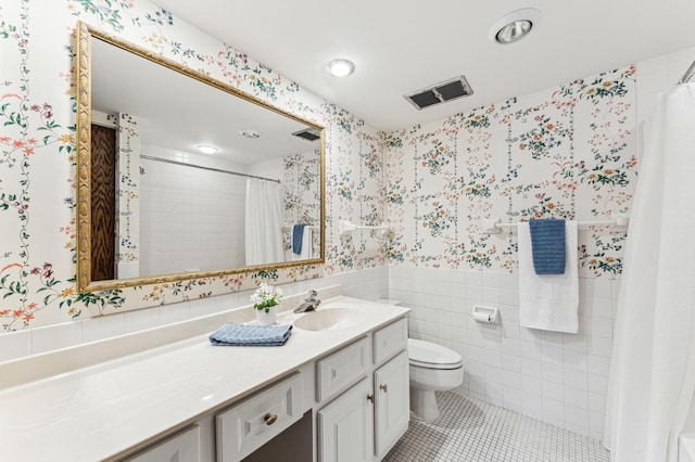 bathroom with vanity, tile patterned floors, toilet, tile walls, and walk in shower