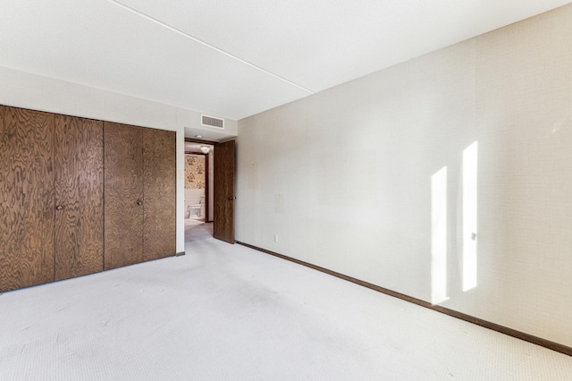 unfurnished bedroom featuring light colored carpet and a closet