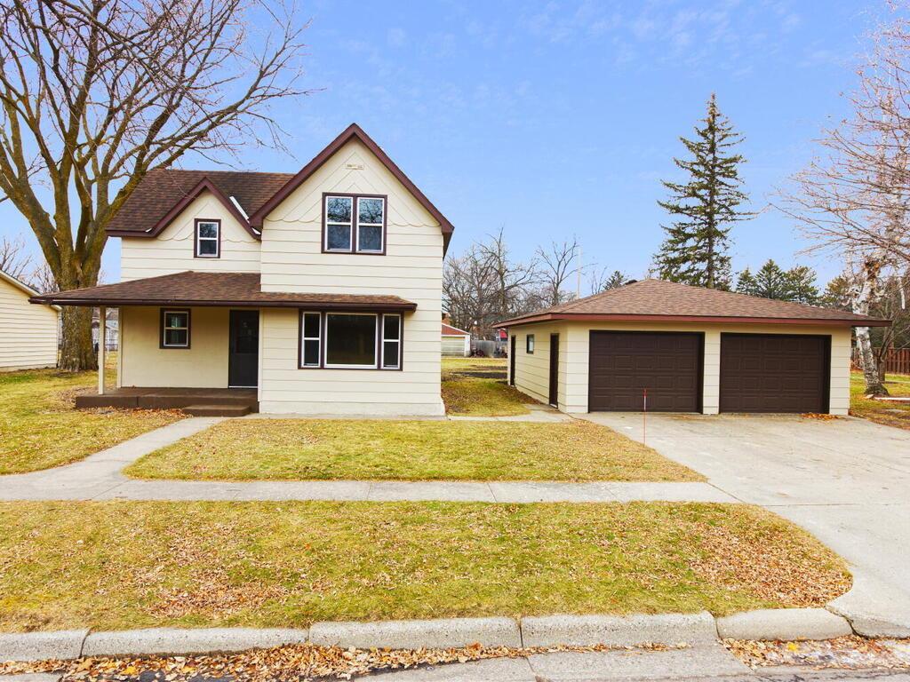 view of front of house with a porch, a front yard, and a garage