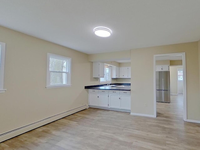 kitchen featuring white cabinetry, stainless steel fridge, a baseboard radiator, and light wood-type flooring