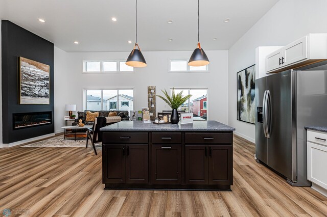 129 Pine Ave, Mapleton, ND 58059 - kitchen featuring stainless steel fridge with ice dispenser, light wood finished floors, white cabinets, a large fireplace, and hanging light fixtures