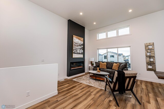129 Pine Ave, Mapleton, ND 58059 - living area with wood finished floors, baseboards, a large fireplace, recessed lighting, and a towering ceiling
