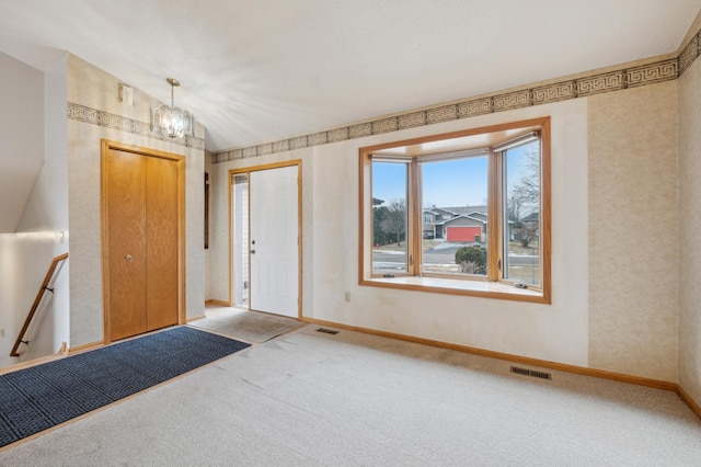 entryway with lofted ceiling, carpet floors, and a chandelier