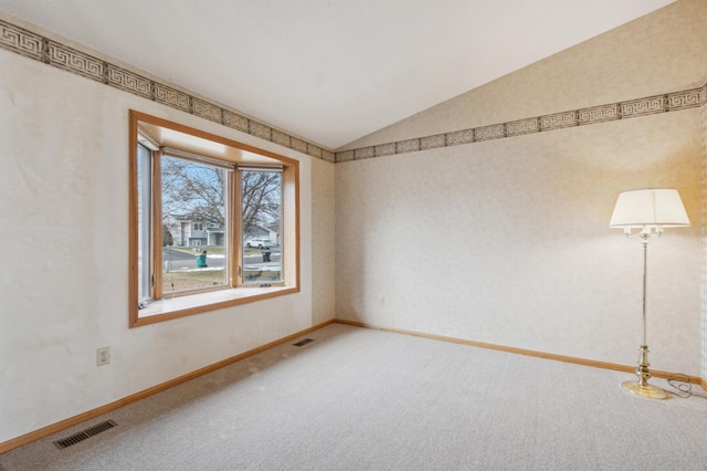 carpeted spare room featuring vaulted ceiling