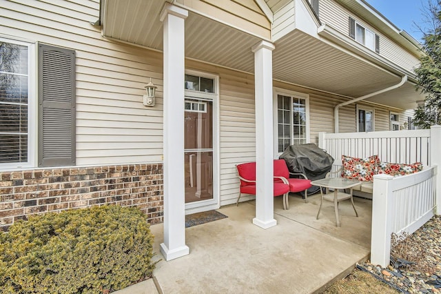 view of exterior entry featuring covered porch and brick siding