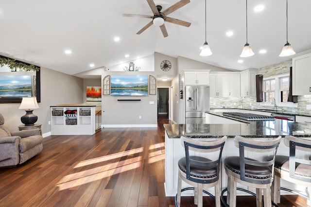 kitchen featuring lofted ceiling, backsplash, white cabinets, decorative light fixtures, and stainless steel appliances