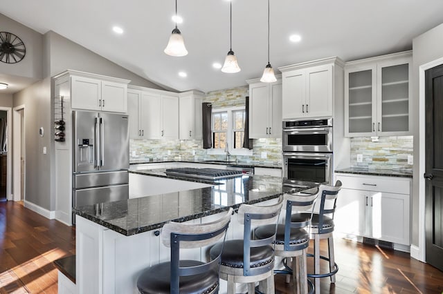 kitchen with stainless steel appliances, pendant lighting, white cabinetry, a kitchen island, and lofted ceiling