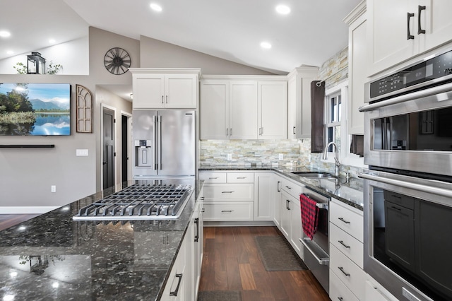 kitchen with white cabinets, appliances with stainless steel finishes, vaulted ceiling, and sink