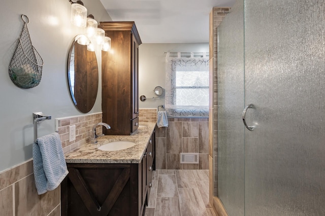 bathroom featuring vanity, a shower with door, and tile walls