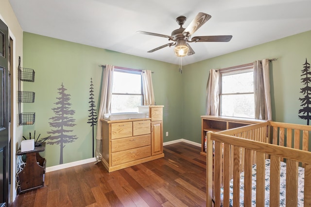 bedroom featuring ceiling fan, dark wood-type flooring, and a nursery area