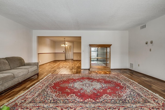 living room featuring wood-type flooring, a notable chandelier, and a textured ceiling