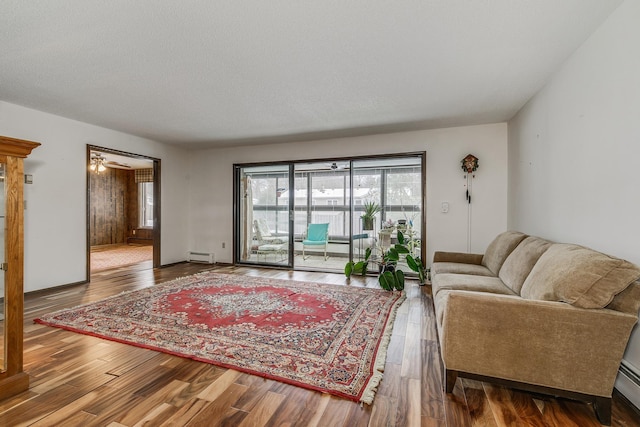 living room featuring ceiling fan, baseboard heating, a textured ceiling, and hardwood / wood-style flooring