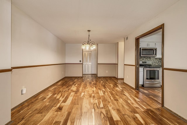 unfurnished dining area featuring hardwood / wood-style floors and an inviting chandelier