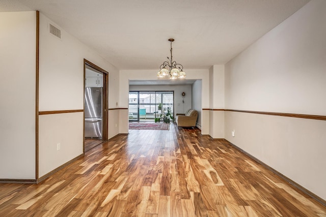 unfurnished room featuring light wood-style floors, a chandelier, and baseboards