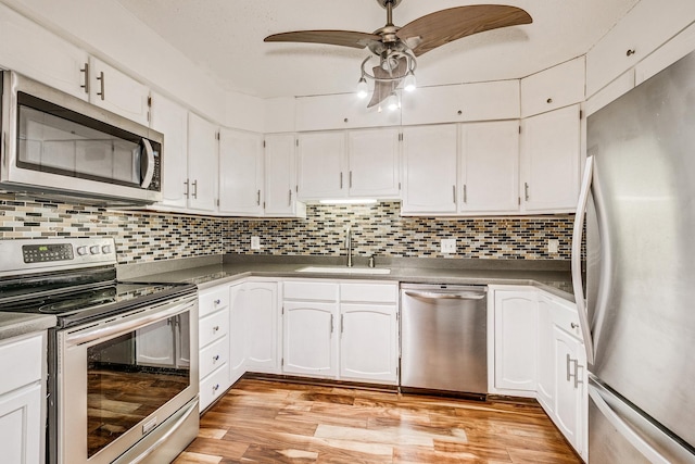 kitchen with appliances with stainless steel finishes, a sink, ceiling fan, white cabinetry, and light wood-type flooring