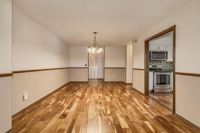 unfurnished dining area featuring light wood finished floors and a chandelier