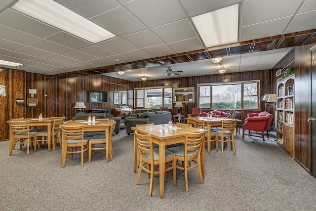 carpeted dining space featuring wooden walls