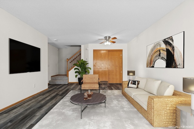 living room featuring ceiling fan, dark wood-type flooring, and a textured ceiling