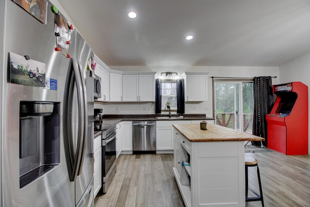 kitchen featuring a kitchen breakfast bar, sink, a kitchen island, white cabinetry, and stainless steel appliances