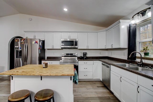 kitchen featuring lofted ceiling, white cabinets, a kitchen breakfast bar, sink, and stainless steel appliances