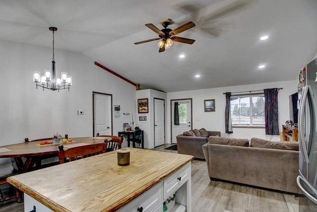 dining room featuring ceiling fan with notable chandelier, light hardwood / wood-style flooring, and lofted ceiling