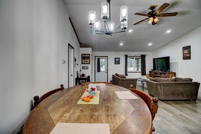 dining room featuring ceiling fan with notable chandelier, light hardwood / wood-style floors, and lofted ceiling