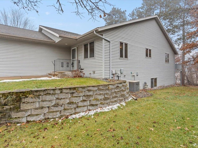 view of side of home featuring a lawn and central AC